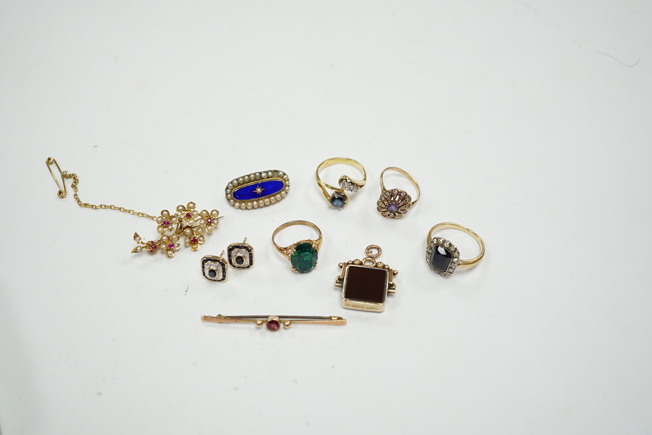 A 750 yellow metal, single stone sapphire and three stone diamond set crossover ring, size, three other yellow metal and gem set rings including a continental 875 white metal and 585 yellow metal, synthetic sapphire or s